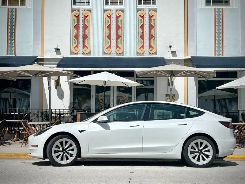 White Tesla Model 3 outside an Art Deco hotel on Ocean Drive, Miami Beach