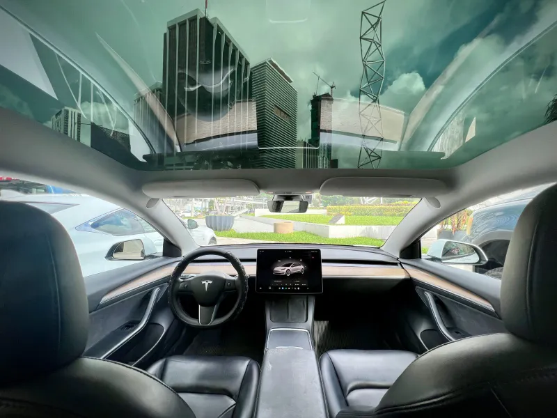 Panoramic glass roof and dashboard inside a white Tesla Model 3