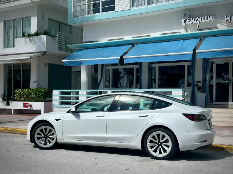White Tesla Model 3 outside the Penguin Hotel on Ocean Drive, South Beach, Miami Beach