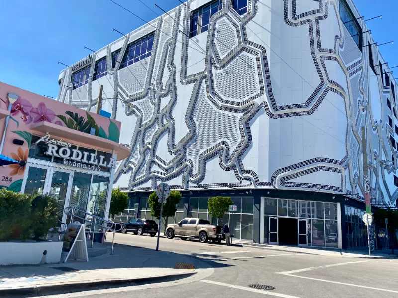 Relief-patterned facade beside a mural-painted café in Wynwood, Miami
