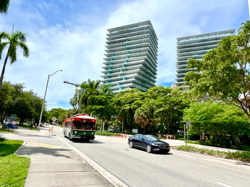 Trolley on a tree-lined street below the Grove at Grand Bay towers, Coconut Grove, Miami