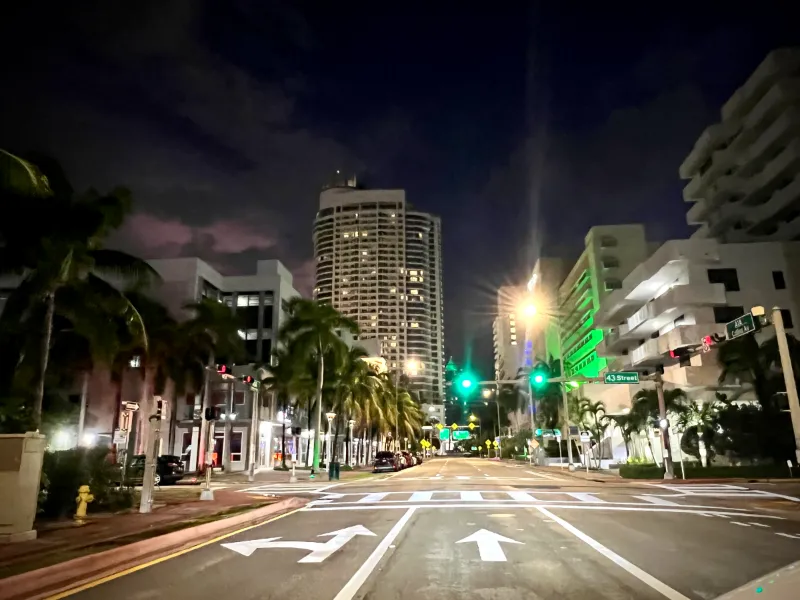 Collins Avenue at 43rd Street at night, between palms and high-rises, Miami Beach